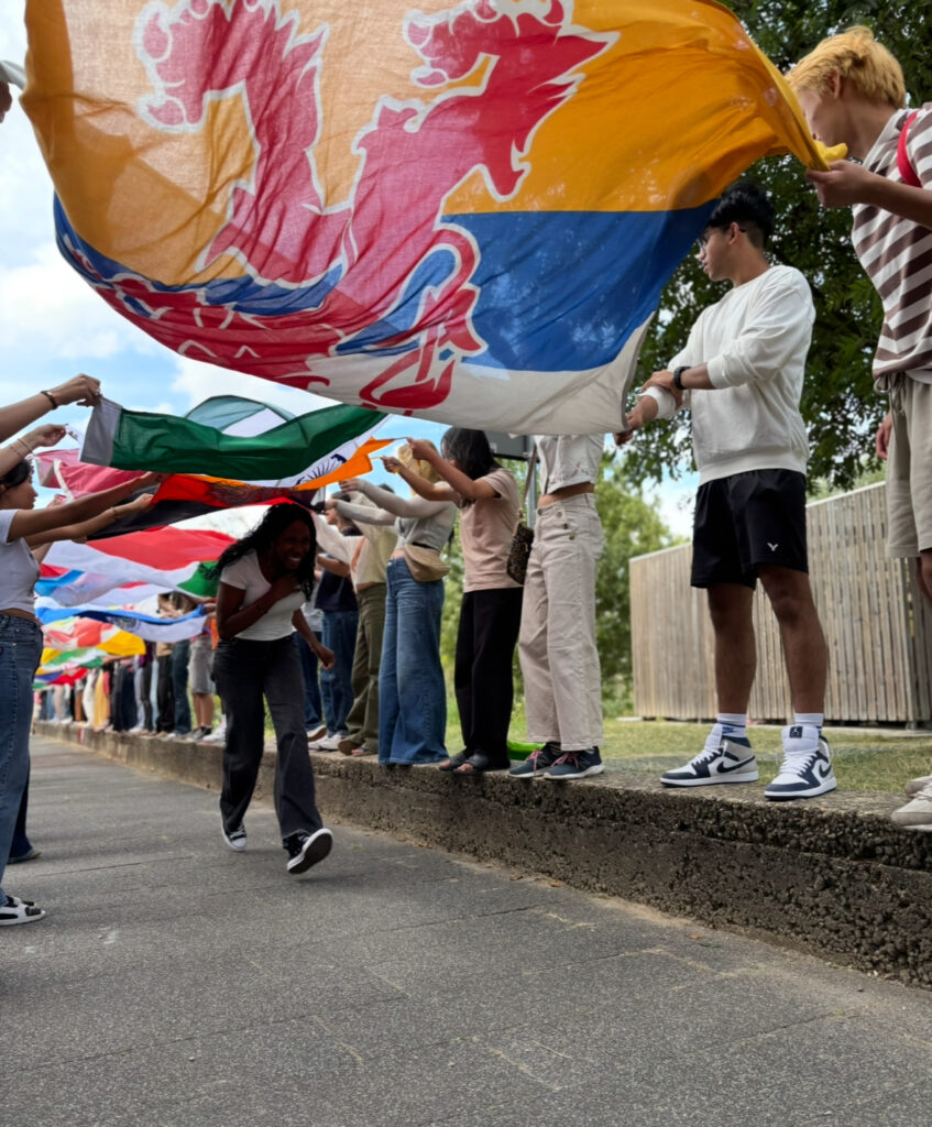 A student runs under the bridge of flags